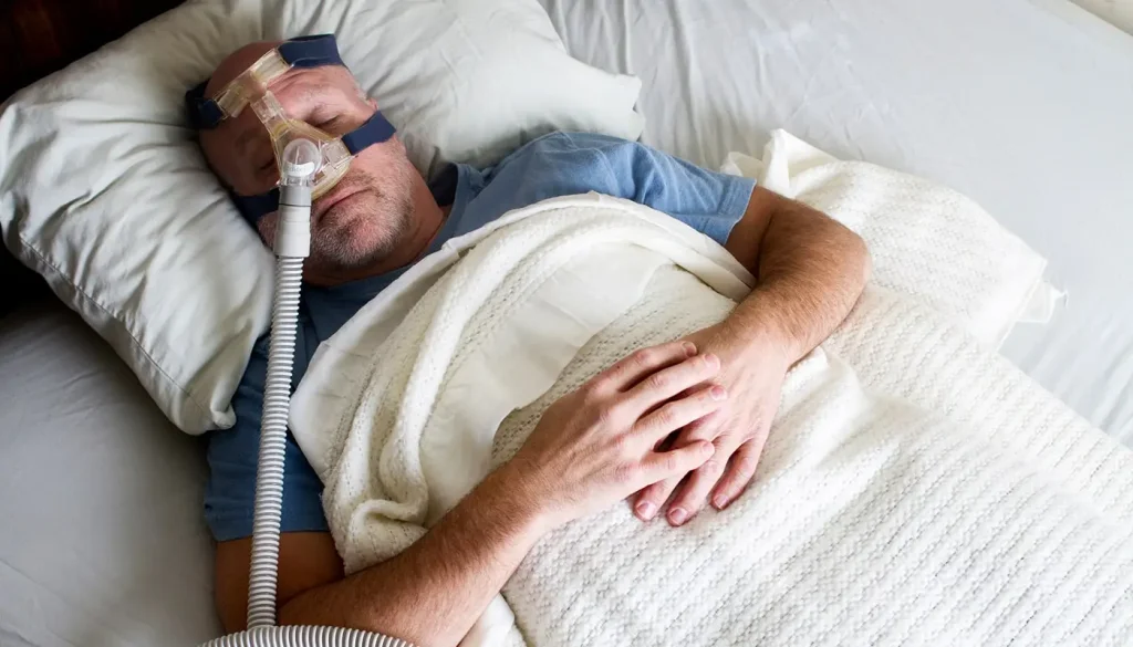While using a dirty CPAP, illness might follow. A middle aged man sleeping using a CPAP machine.